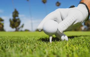 a person's hand holding a ball in a grassy field